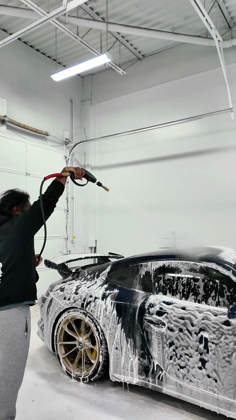 The same Porsche 911 GT3 covered in foam during the prep wash in an Ontario bay