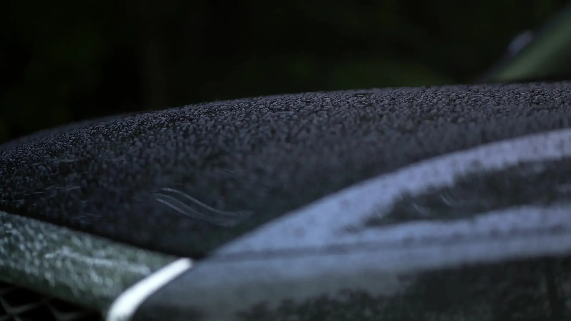 Macro of water beading on the dark coated edge of a car hood
