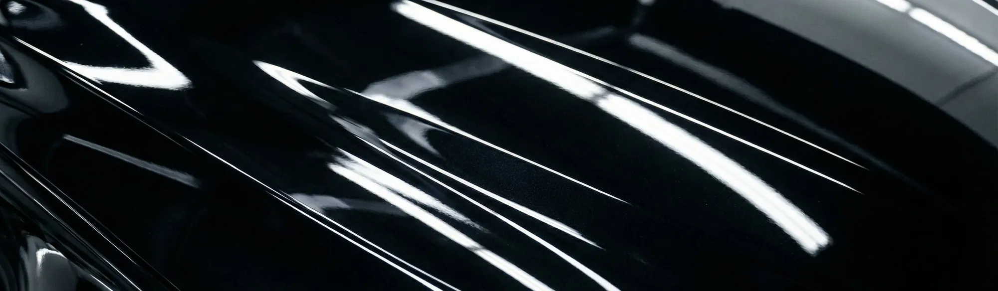 Extreme close up of black gloss paint under long soft highlights