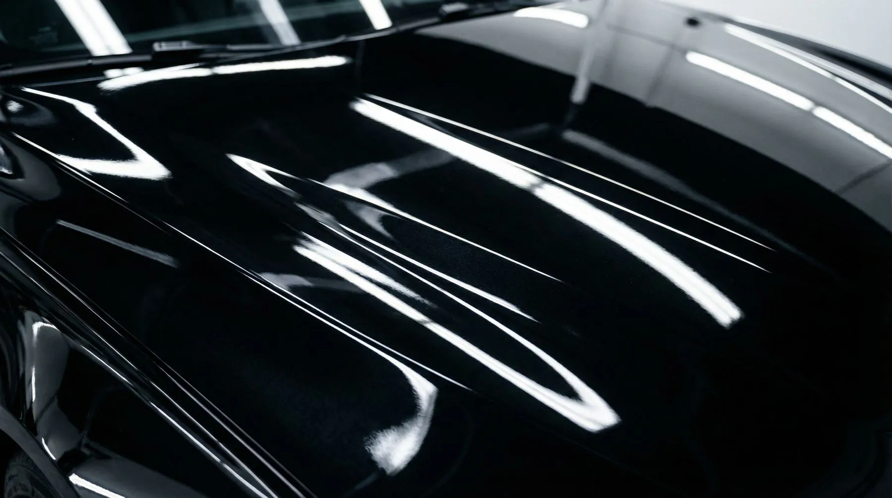 Close up of black gloss paint carrying long soft light streaks