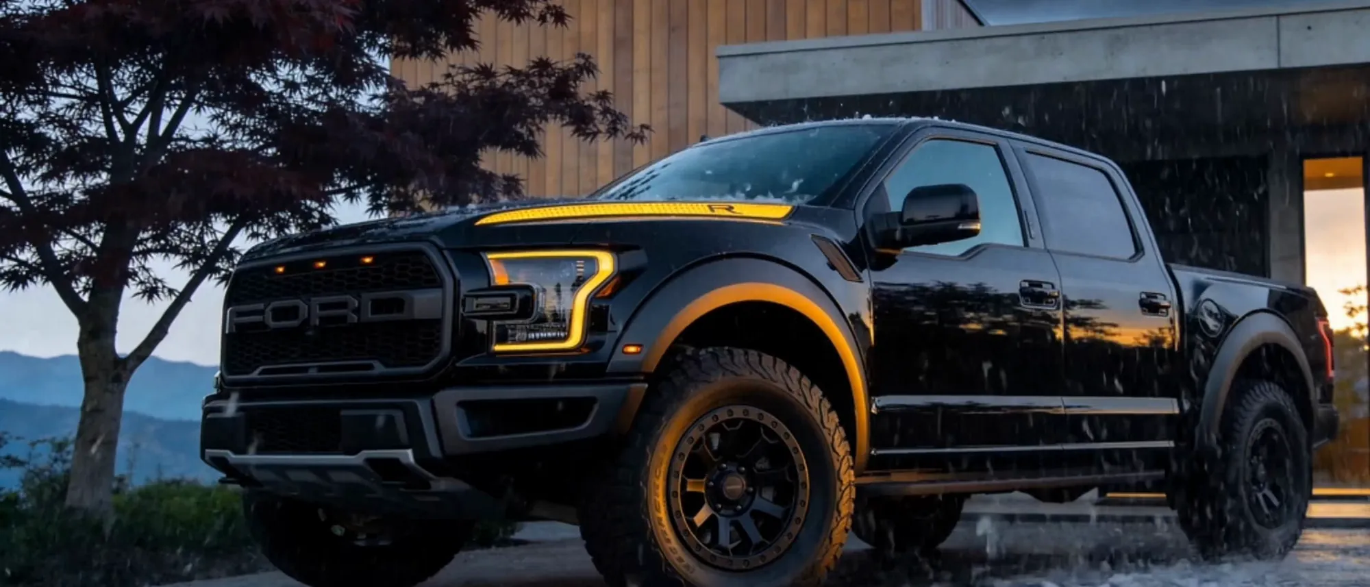 A black pickup in the rain at dusk, water beading off the coated paint